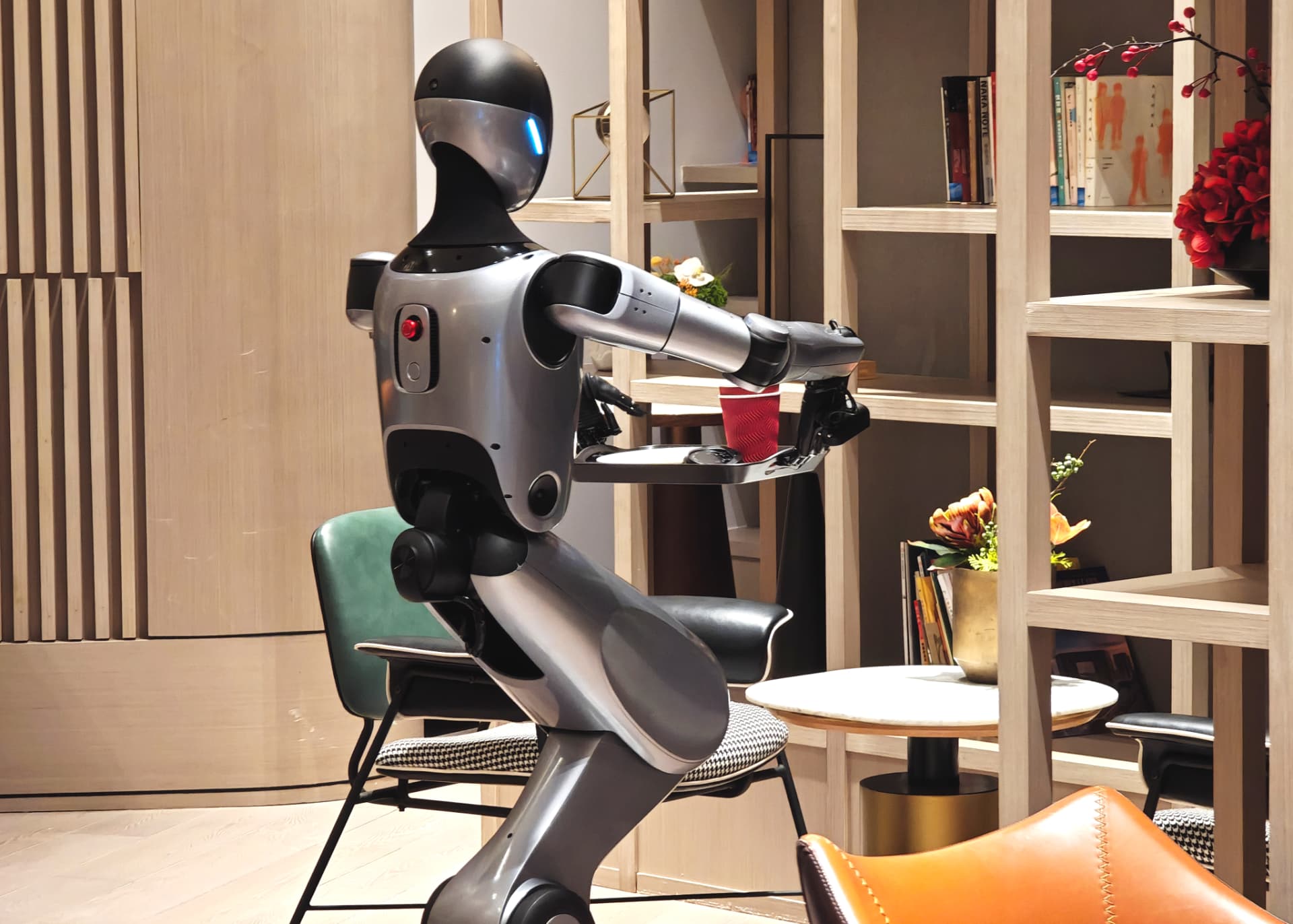 KEENON XMAN-R1 humanoid service robot carrying a tray of drinks through a lounge