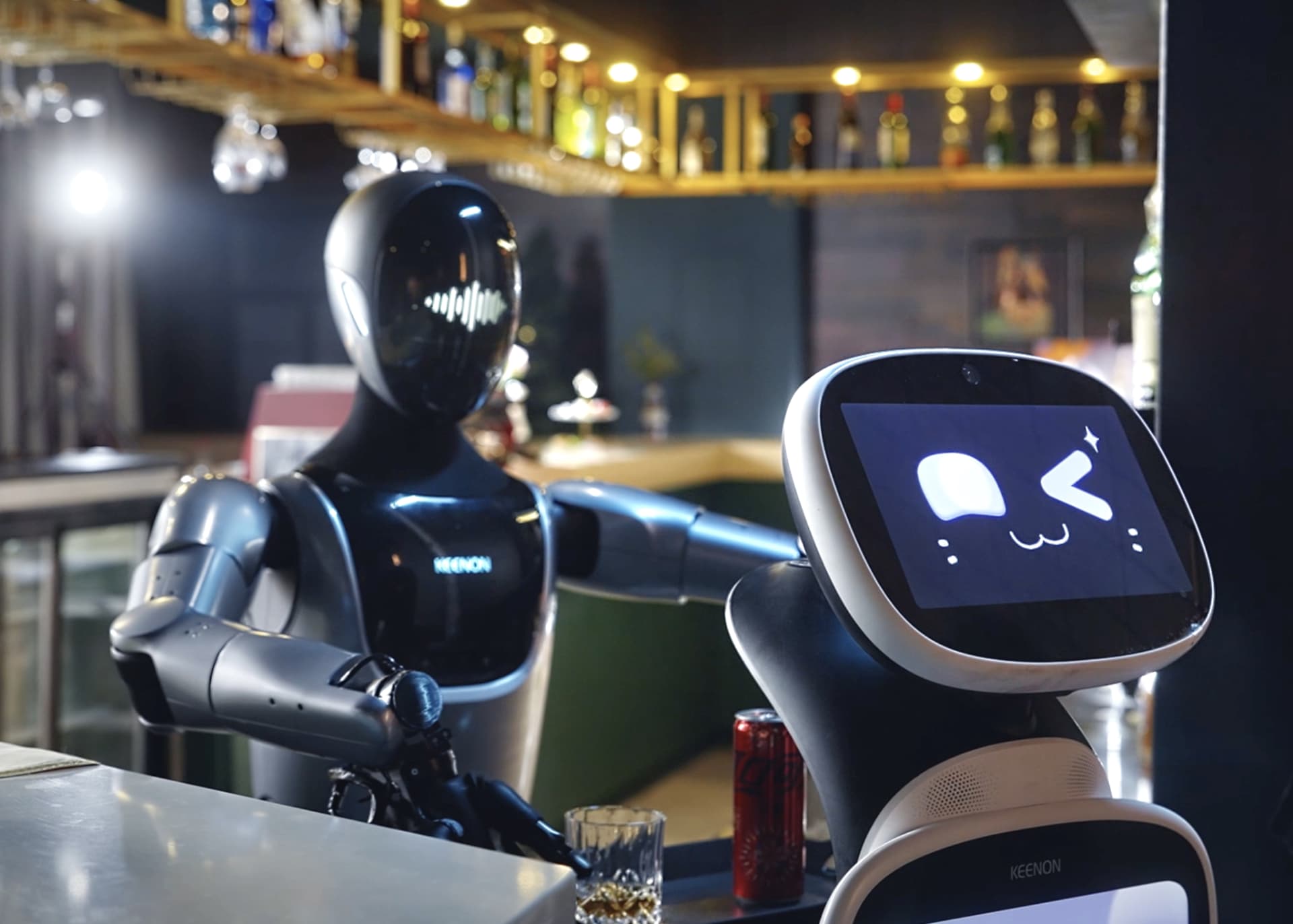 KEENON XMAN-R1 humanoid service robot behind a bar alongside a smaller KEENON delivery robot